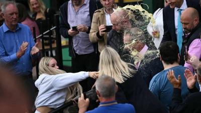 Title: Woman Drenches Face of British Party Leader with Drink